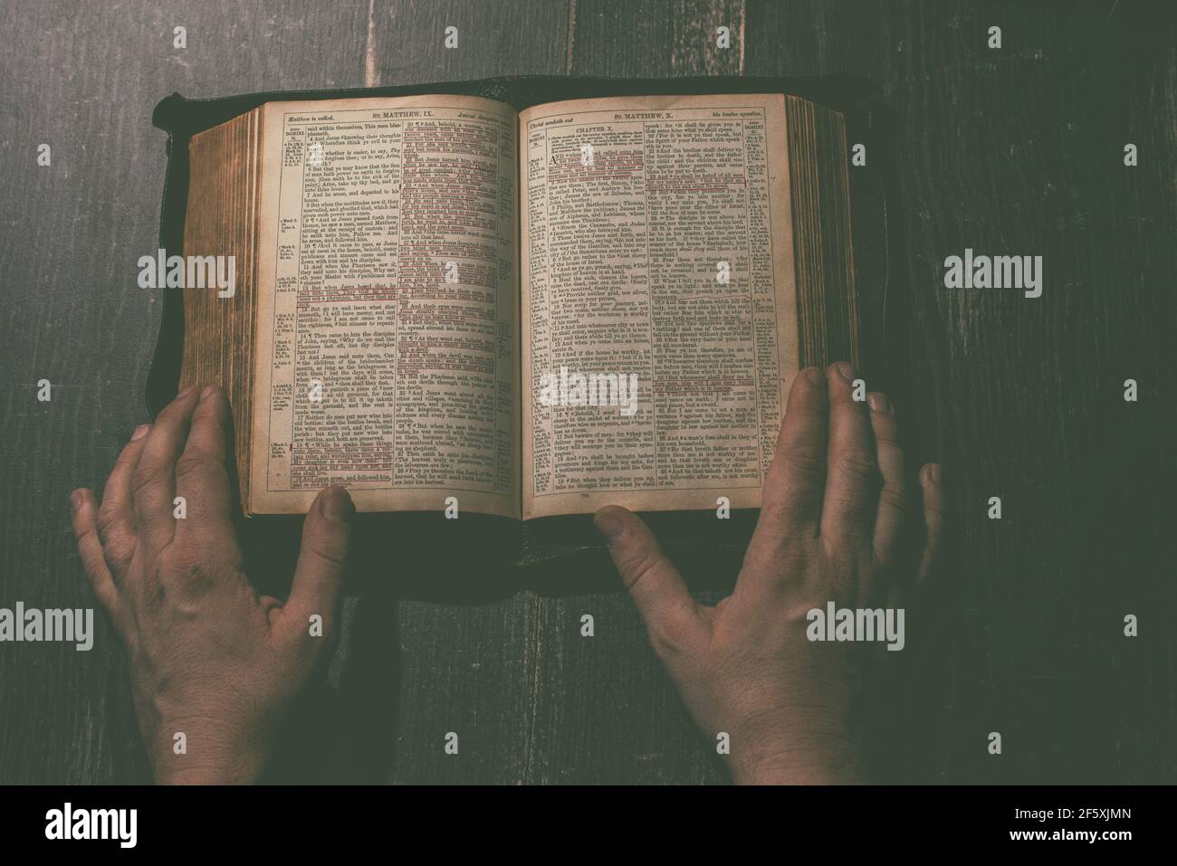 Prayer, man hands over an old open book Holy Bible, wooden desk background. Stock Photo