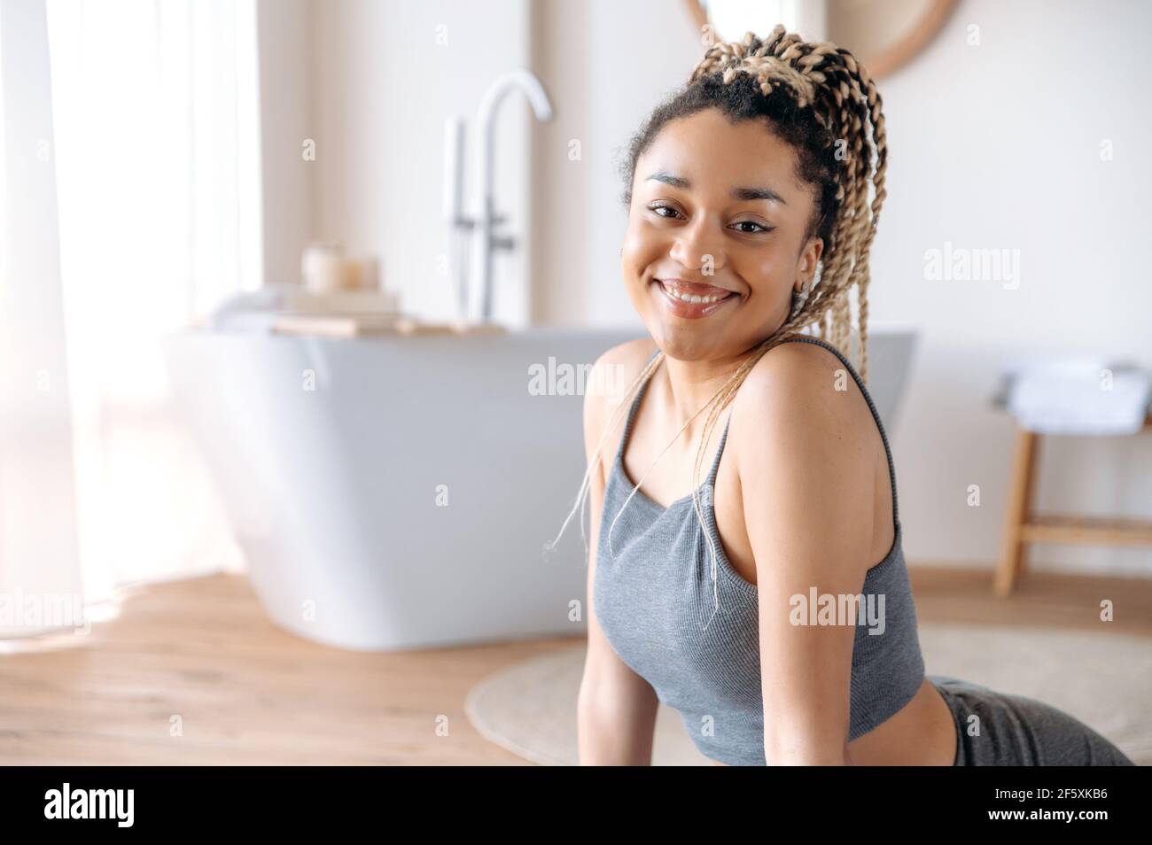 https://c8.alamy.com/comp/2F5XKB6/cute-athletic-african-american-brunette-girl-with-dreadlocks-in-sportswear-sitting-on-the-floor-on-a-fitness-mat-doing-a-warm-up-before-home-sport-workout-looking-at-the-camera-smiling-happily-2F5XKB6.jpg