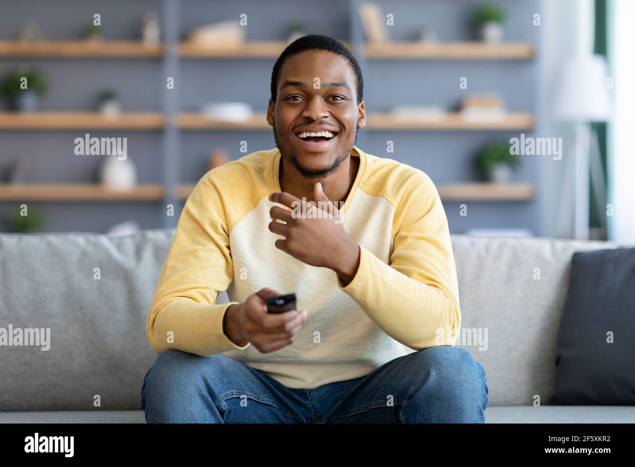 Laughing black guy watching comedy on TV at home Stock Photo