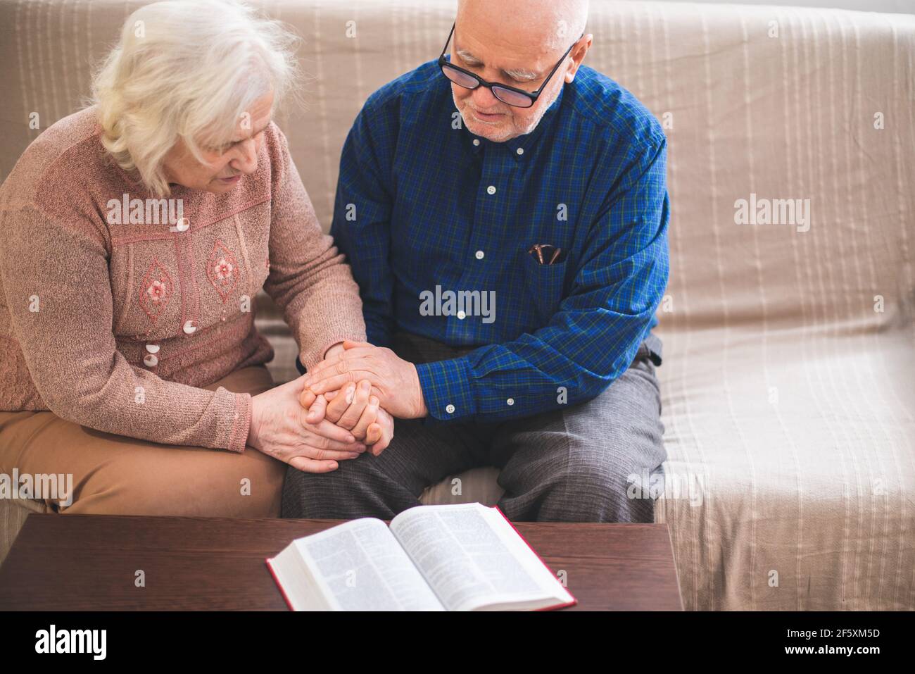 Elderly couple reading bible and pray together at home. Stock Photo