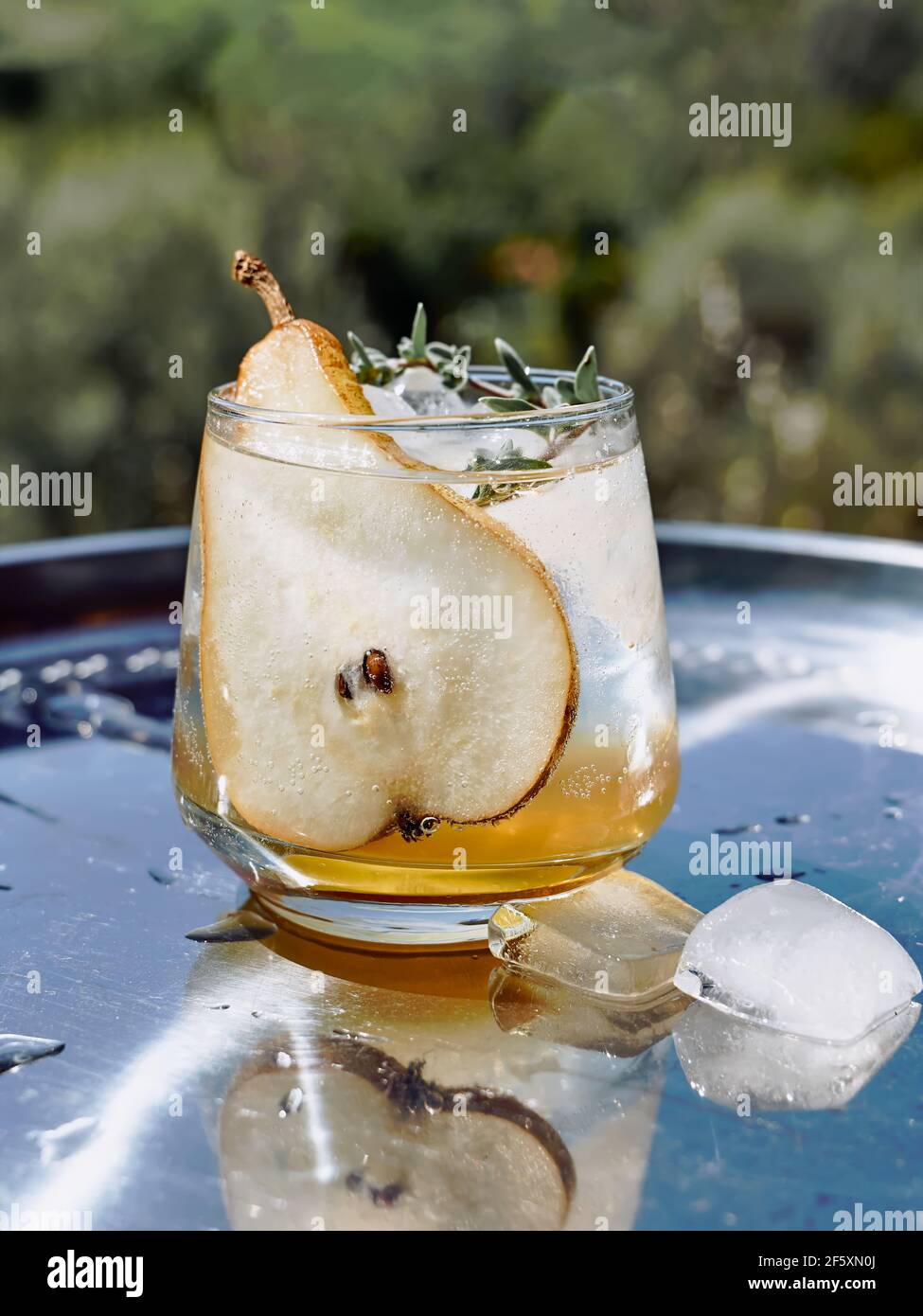 Fresh and healthy cocktail or mocktail with pear, ice and herbs on the steel tray. Refreshing drink in the garden. Stock Photo