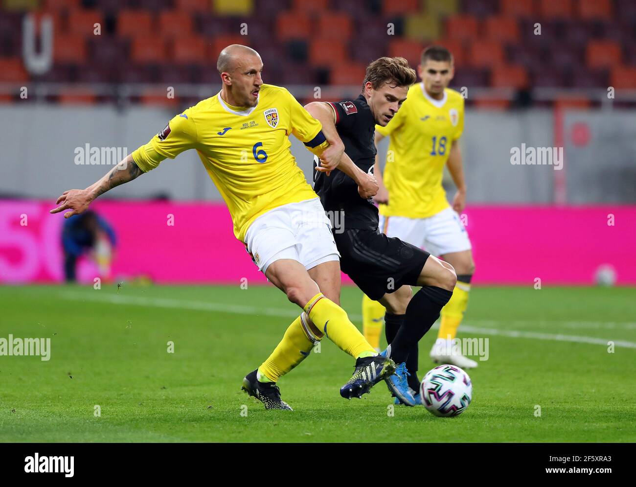Bukarest, Romania. 28th Mar, 2021. Football: World Cup Qualification Europe, Romania - Germany, Group Stage, Group J, Matchday 2 at Arena Nationala. Germany's Joshua Kimmich (m) and Romania's Vlad Chiriches (l) battle for the ball. IMPORTANT NOTE: In accordance with the regulations of the DFL Deutsche Fußball Liga and the DFB Deutscher Fußball-Bund, it is prohibited to use or have used photographs taken in the stadium and/or of the match in the form of sequence pictures and/or video-like photo series. Credit: Stefan Constantin/dpa/Alamy Live News Stock Photo
