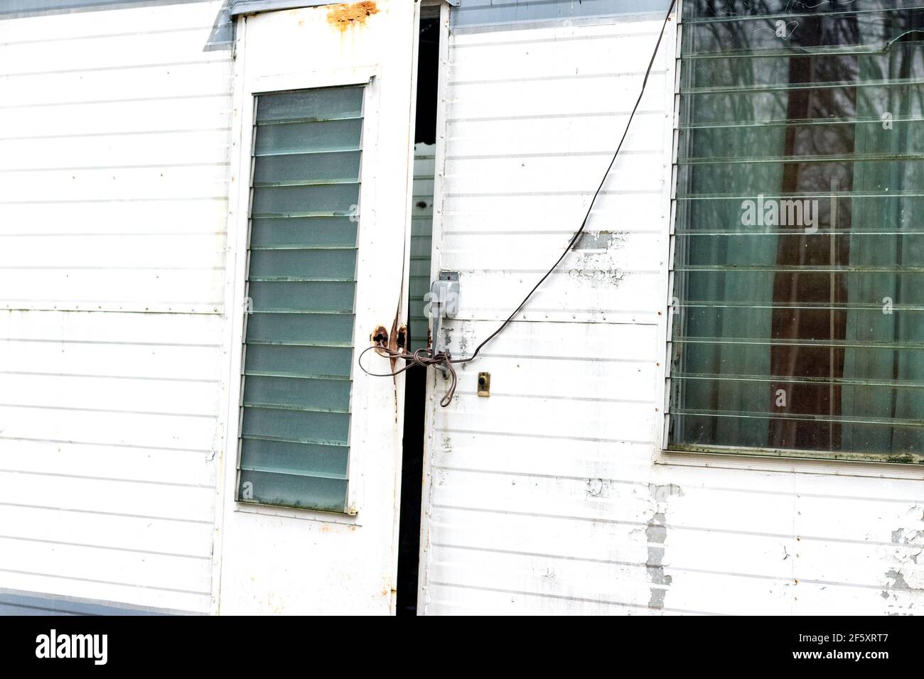 An old trailer door with glass crank windows is rigged shut with wire from the outside Stock Photo