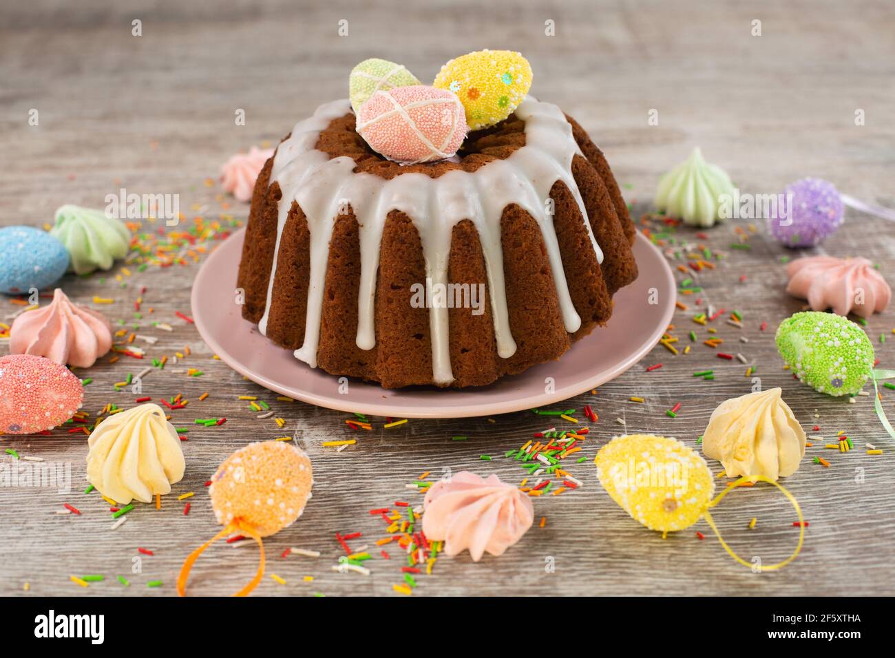 Glazed easter cake decorated with mini eggs candy on wooden table. Happy Easter Holidays. Stock Photo