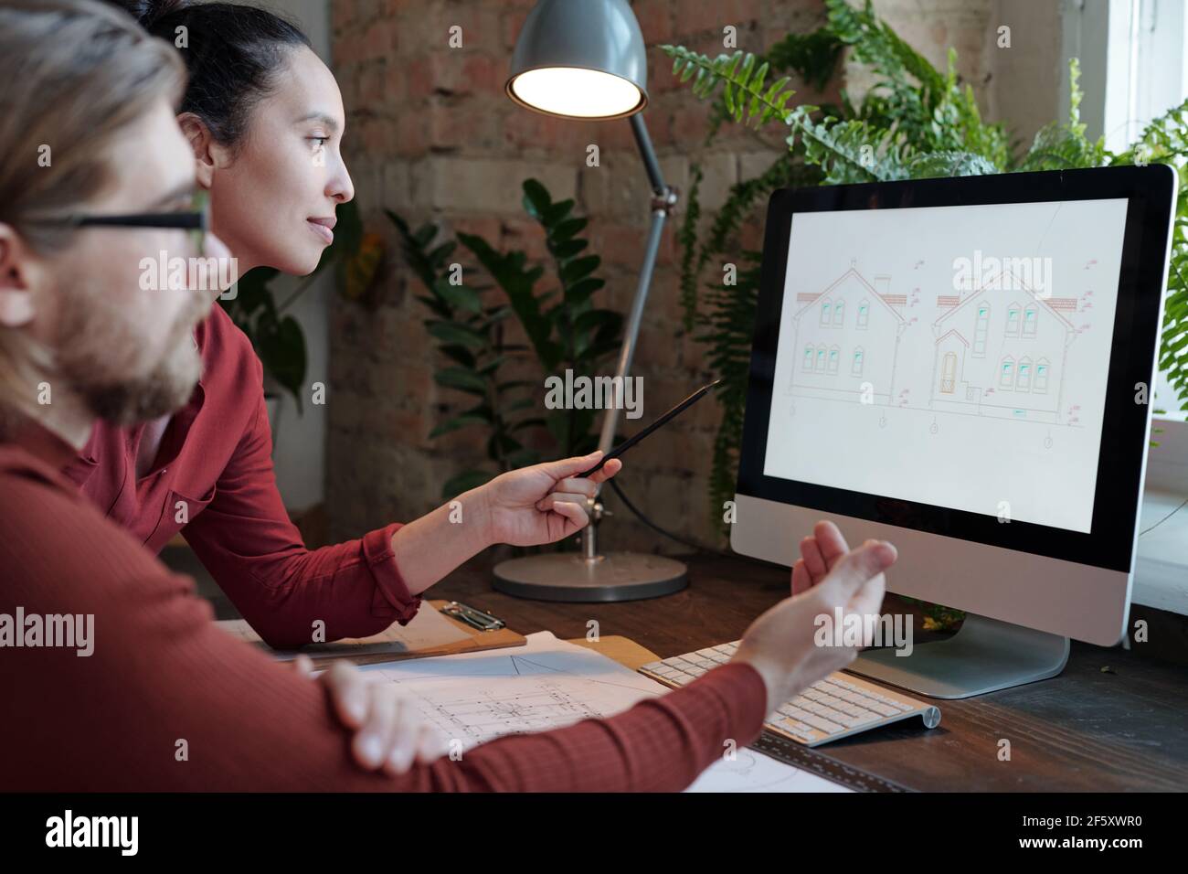 Young female architect and her male colleague discussing new project in ...