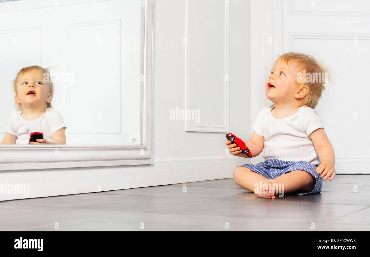 Happy toddler boy play with toy car near mirror Stock Photo Alamy