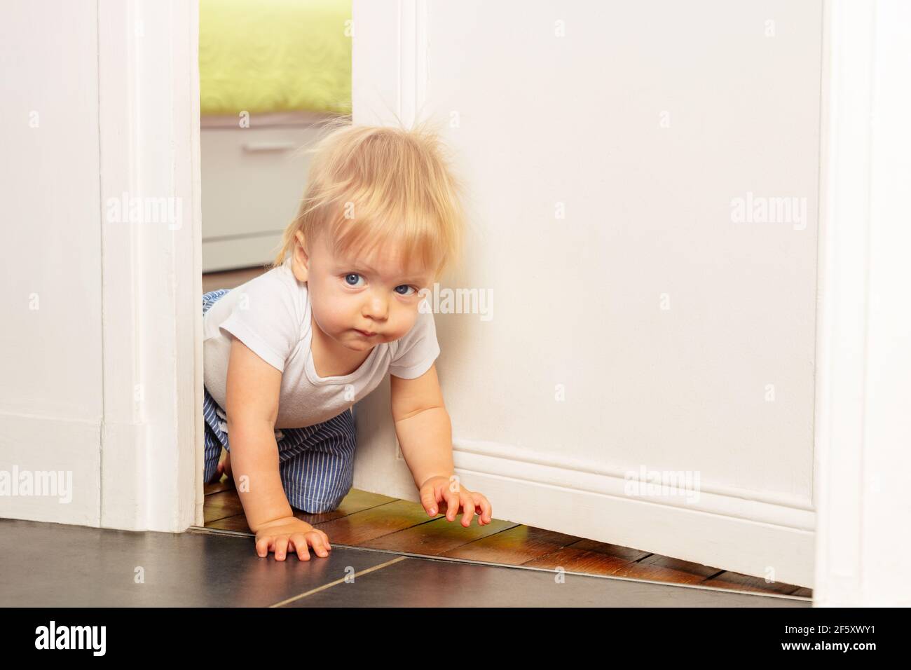Toddler crawl out of the room with serious face Stock Photo Alamy