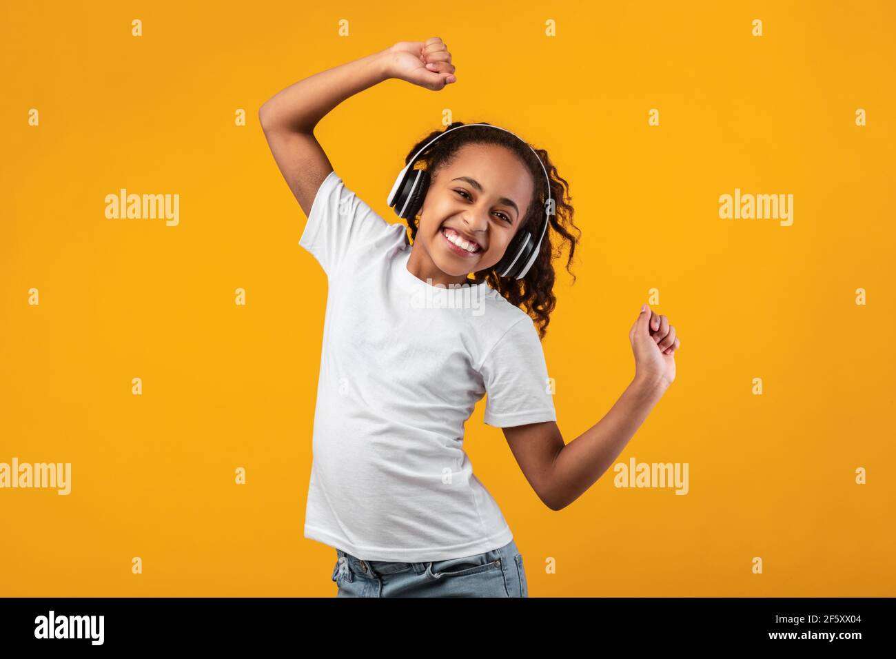 Smiling Black Girl Listening To Music In Headset And Dancing Stock ...
