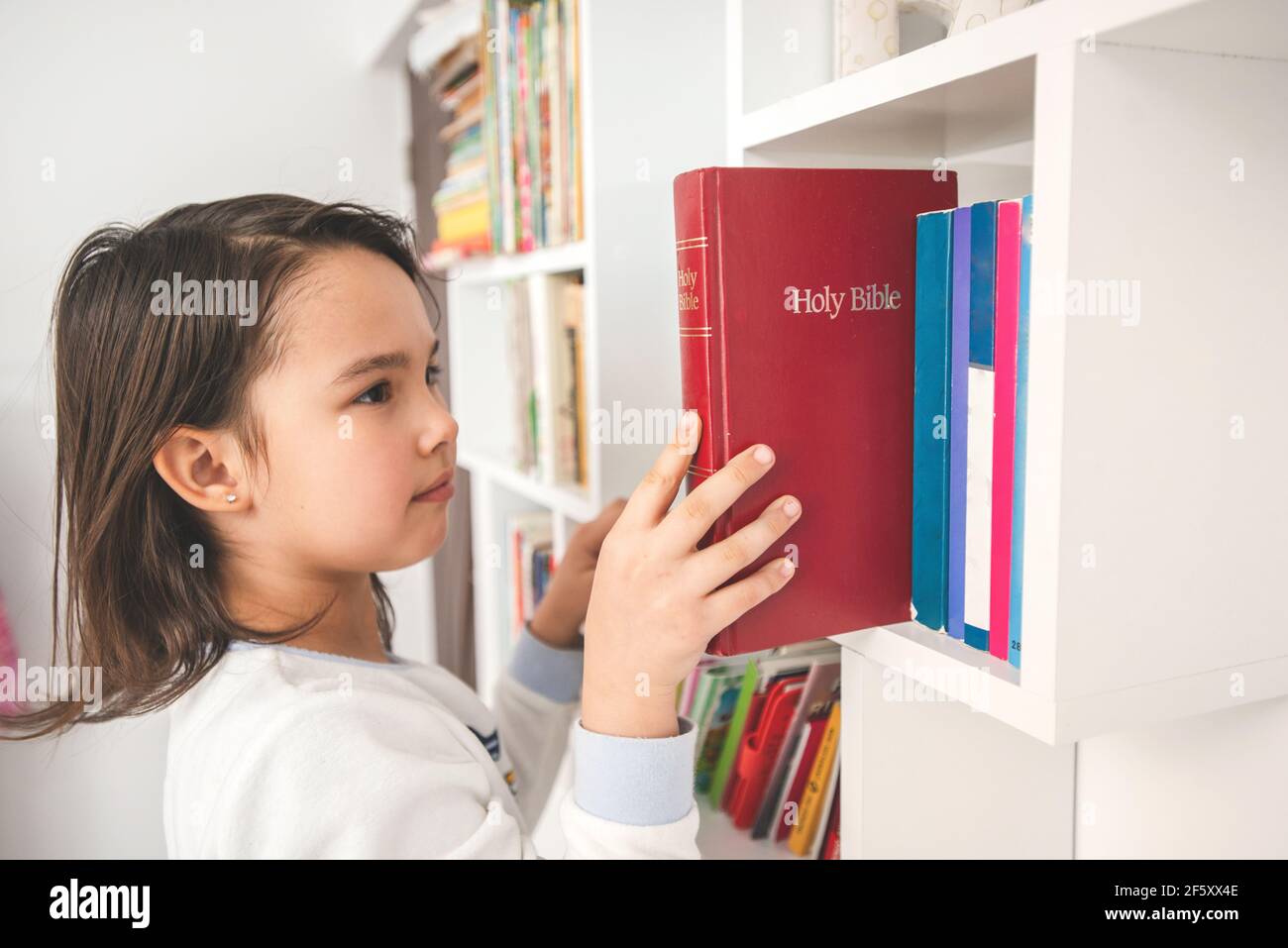 Little taking the bible from her library Stock Photo