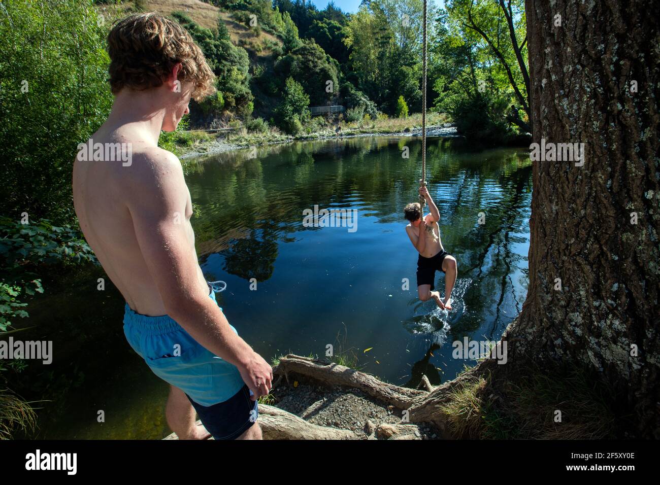 Youths swim and play at Black Hole, Maitai River, Nelson, New Zealand. Stock Photo