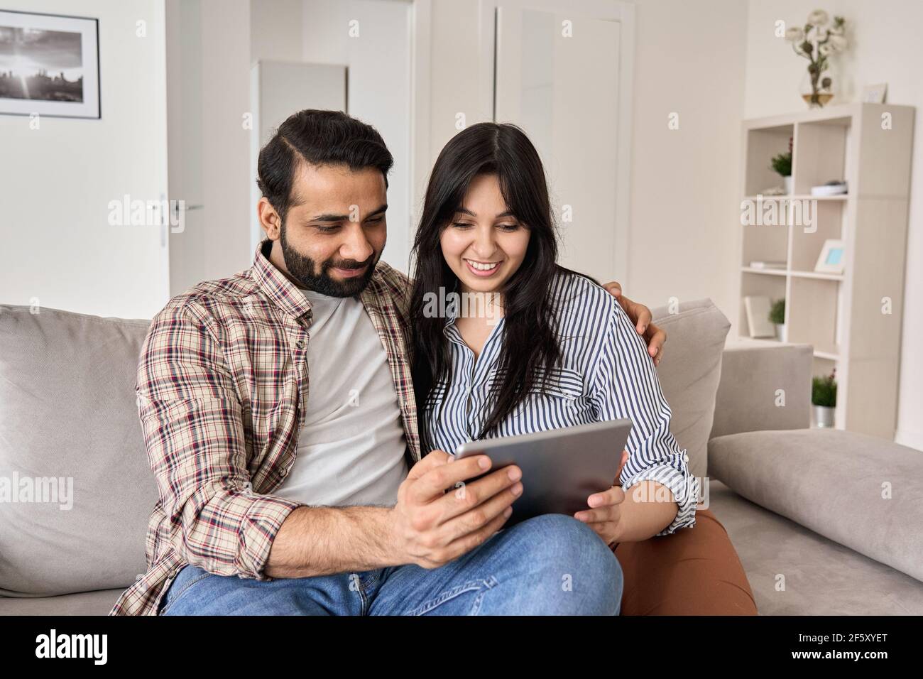 Happy indian family couple using digital tablet computer at home. Stock Photo