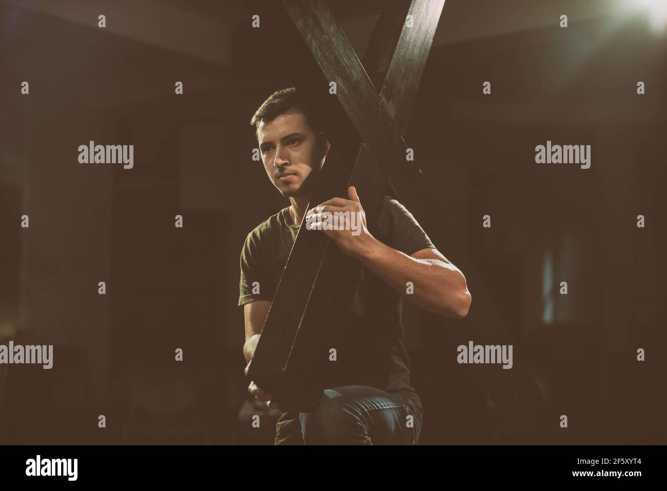 Young man carrying a wooden cross. Stock Photo