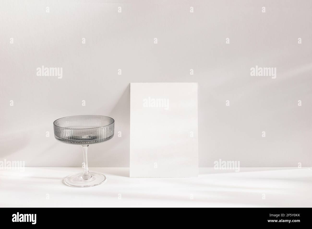 Modern summer still life scene. Grey chanpagne textured glass with drink in sunlight with long shadows. Blank greeting card mock-up. Empty copy space Stock Photo