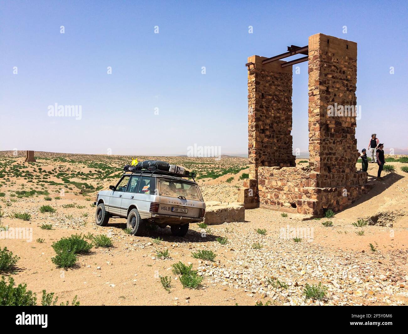 Zaida, Morocco - April 10, 2015. Old vintage silver off road car with travelers by stone water well in desert Stock Photo