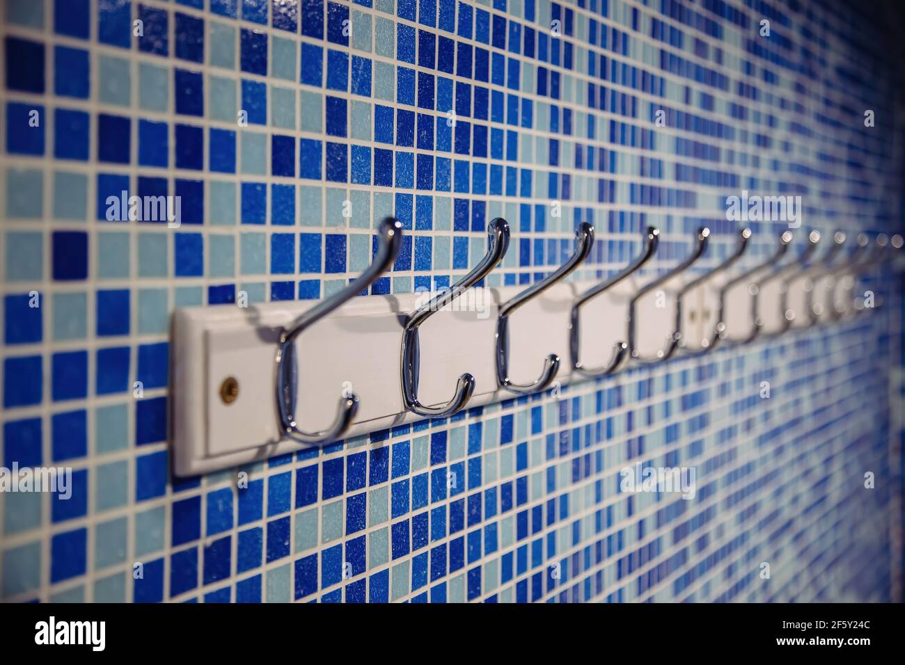 Metal hanger hooks on blue tiled wall. Stock Photo