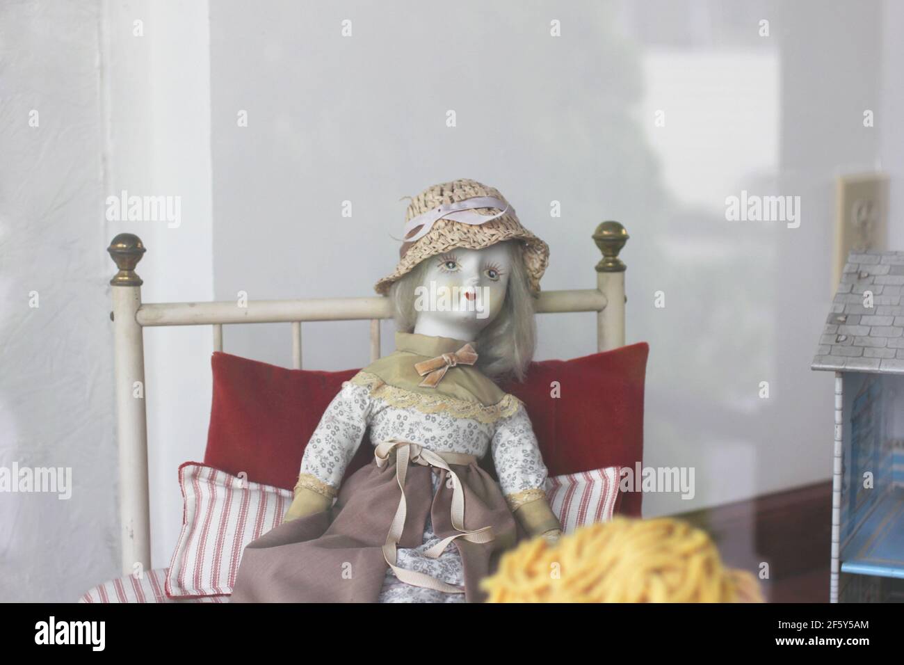 Antique porcelain doll all dressed up with hat in a curiosity shop window Stock Photo