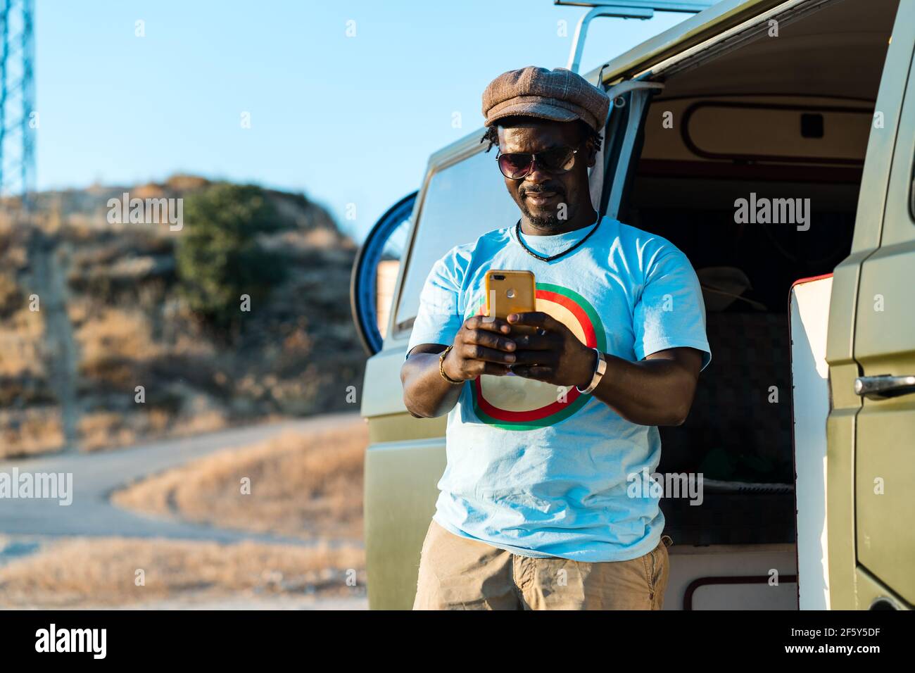 black man with glasses, and mobile phone in camper van Stock Photo