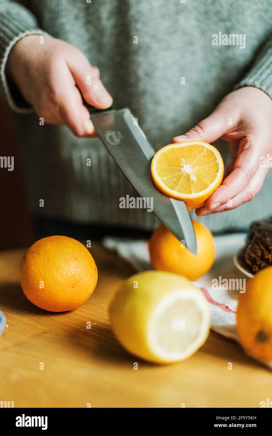 Anonymous woman in her kitchen at home slicing oranges with a sh Stock Photo