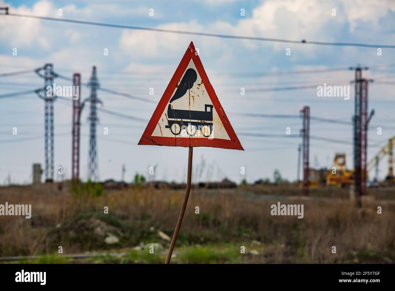 Sokolovo-Sarbay Mining and processing plant. Hand-made warning sign 'Train'. Blue sky and blurred electric towers and wires. Stock Photo