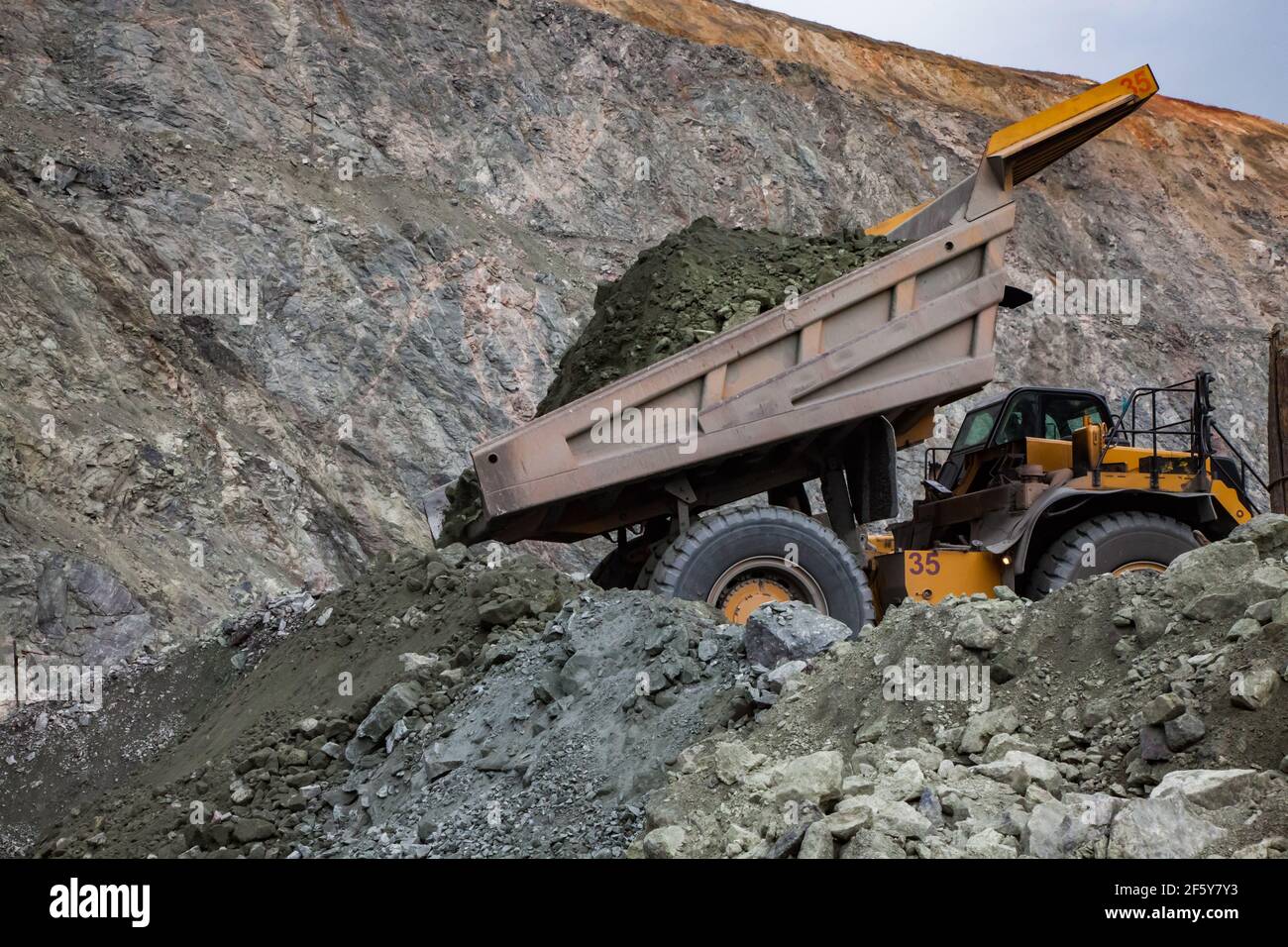 Rudny/Kazakhstan - May 14 2012:  Open-pit mining iron ore in quarry. Caterpillar quarry truck dumping car. Stock Photo