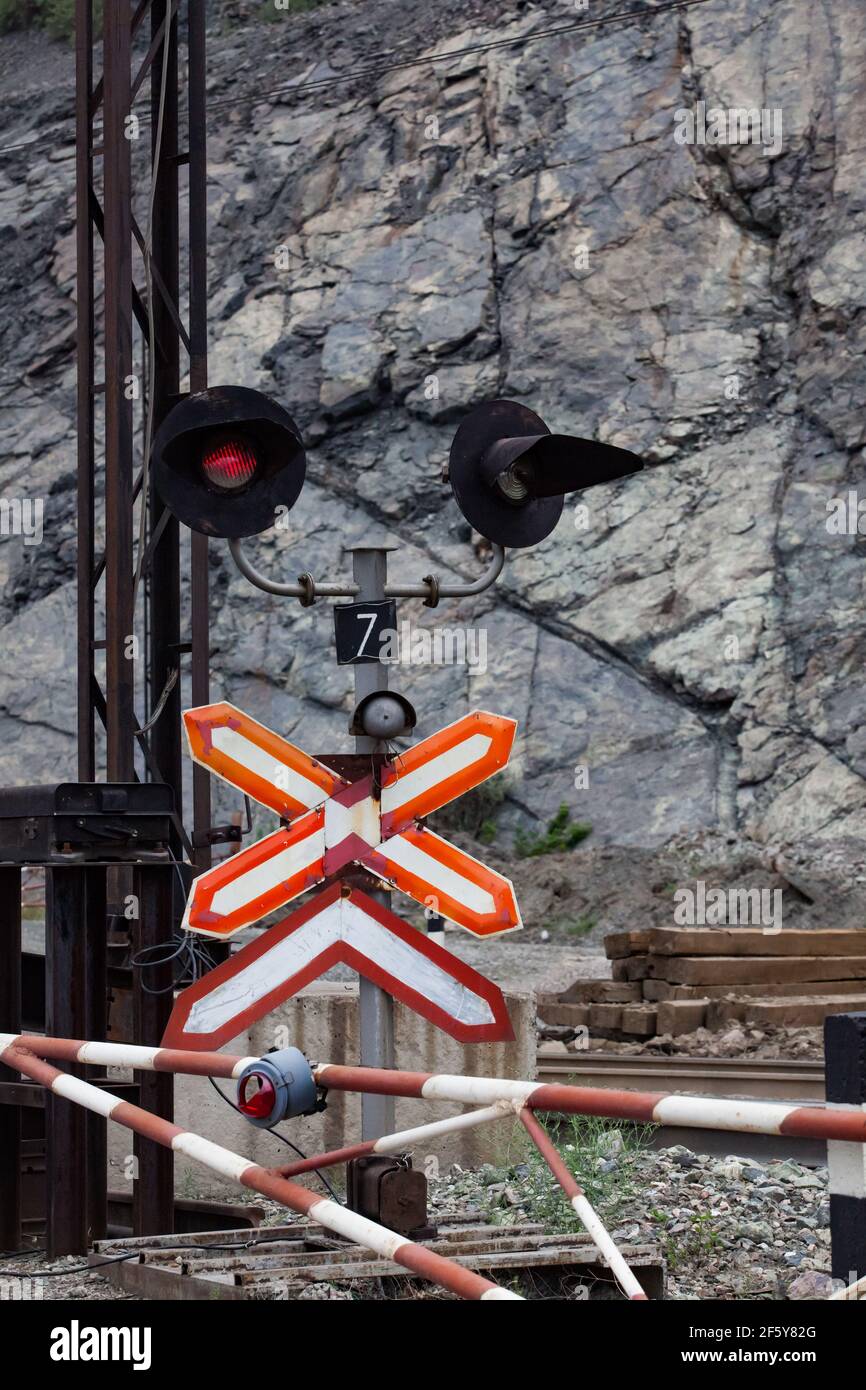 Open-pit mining iron ore. Railway down in quarry. Road sign and red stop light on cross. Rocks of minerals on background. Stock Photo
