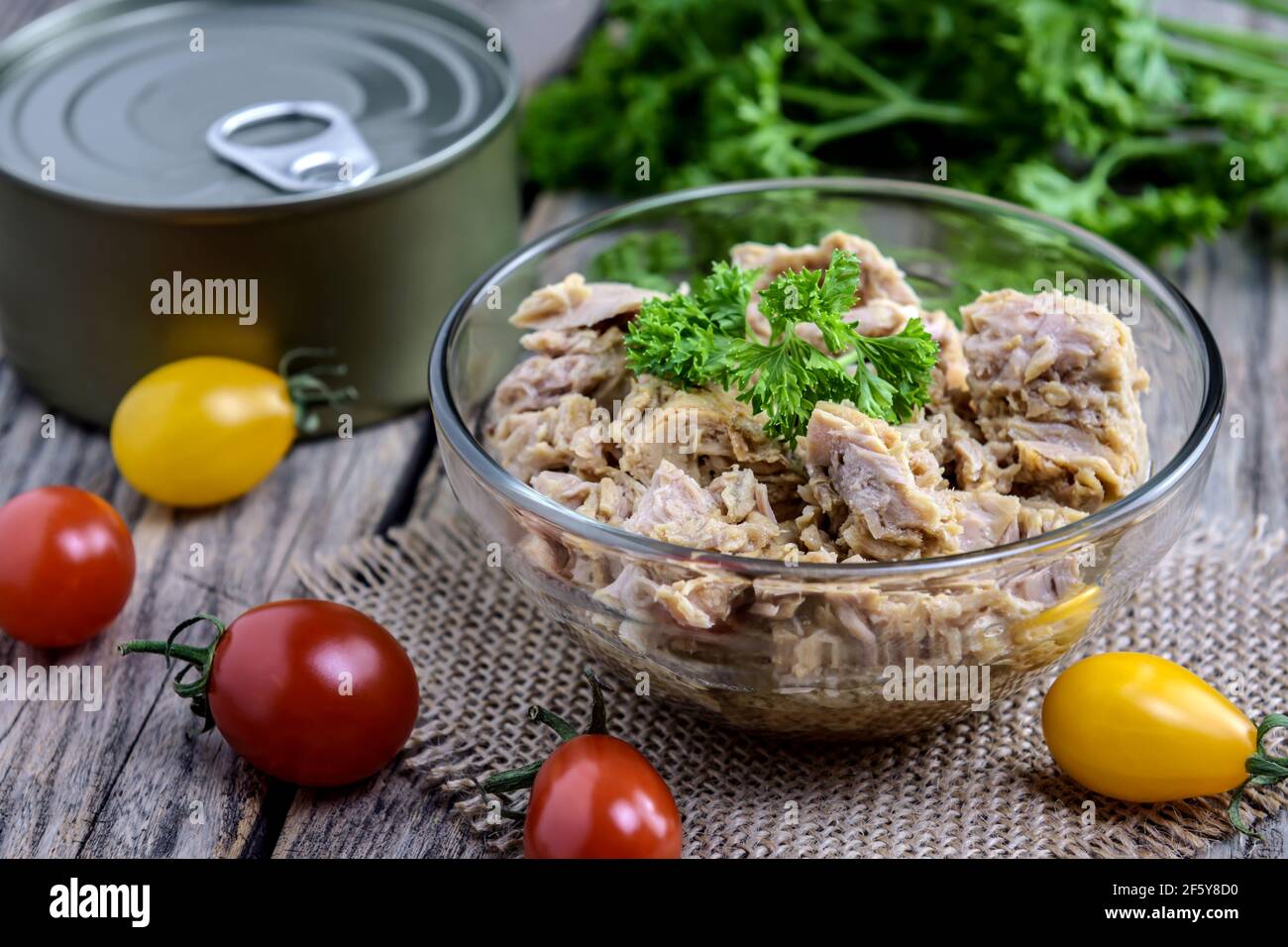 Portion of tuna salad with fresh parsley and cherry tomato on rustic wooden table. Selective focus. Stock Photo