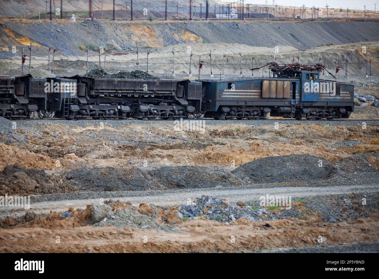 Rudny/Kazakhstan - May 14 2012:  Open-pit mining iron ore. Railway  train and diesel locomotive in quarry transporting ore in wagons to concentrating Stock Photo