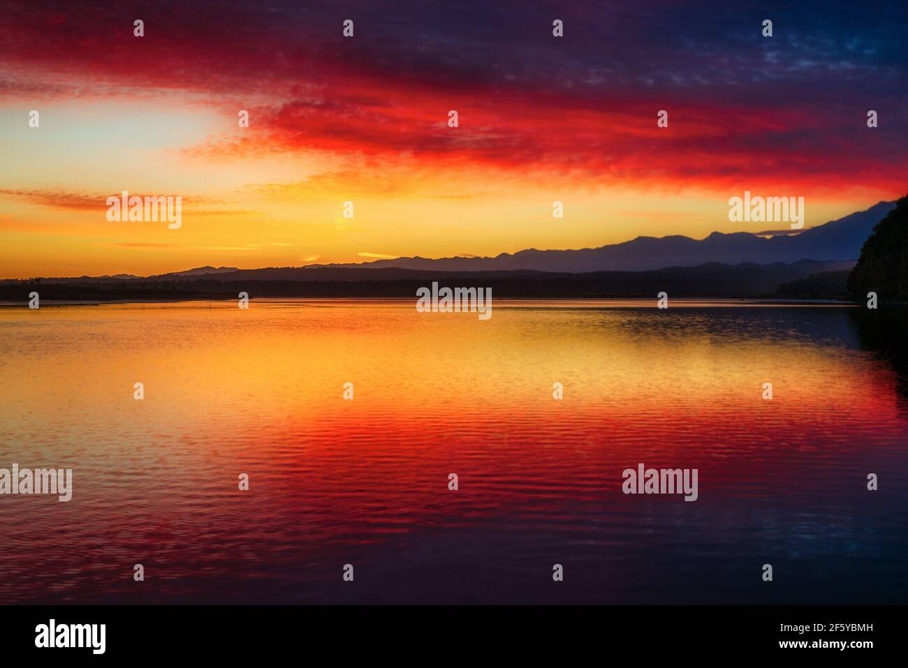 Amazing red and yellow sky colour reflected in Okarito Lagoon with a ...