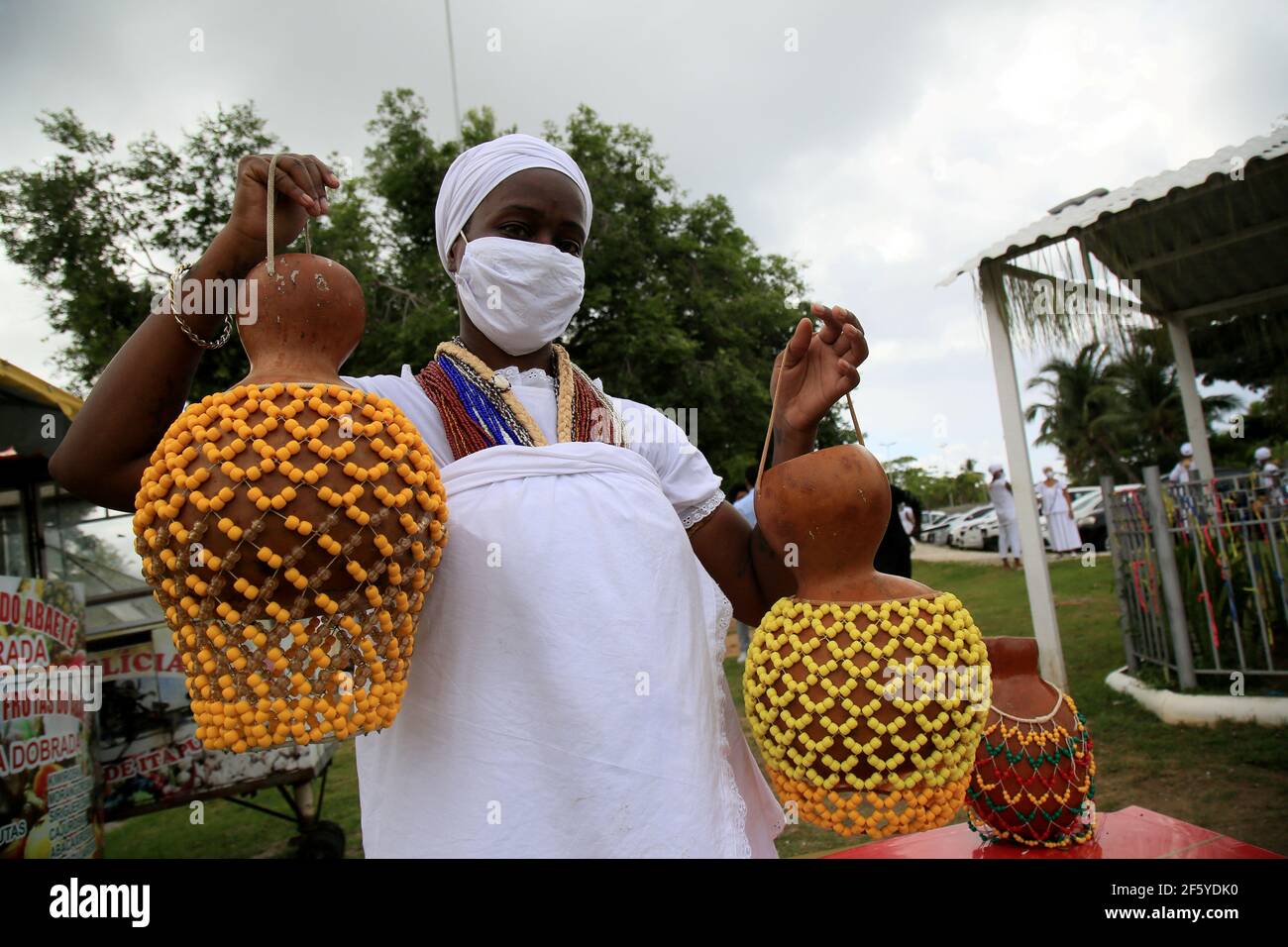 salvador, bahia, brazil - january 6, 2021: adept of candomble holds the xequere, also known as abe e agbe, a percussion musical instrument made of gou Stock Photo