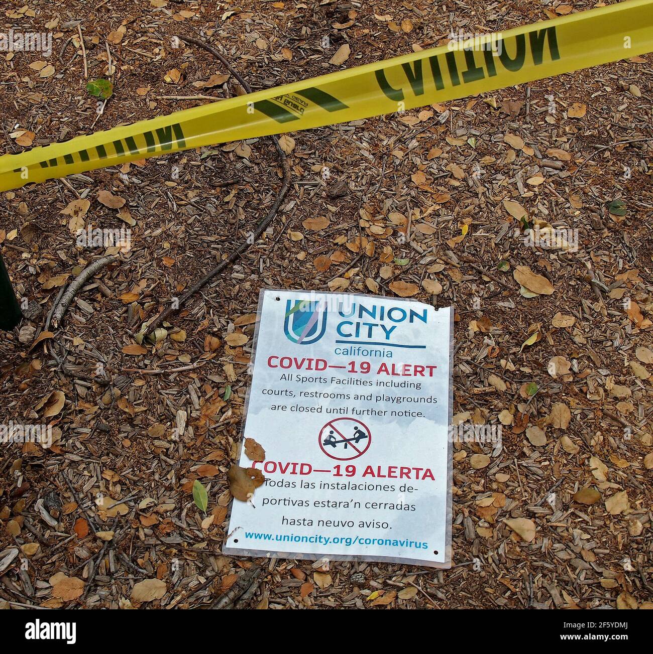 Covid 19 pandemic closure sign and yellow  warning tape in a park in Union City, California Stock Photo