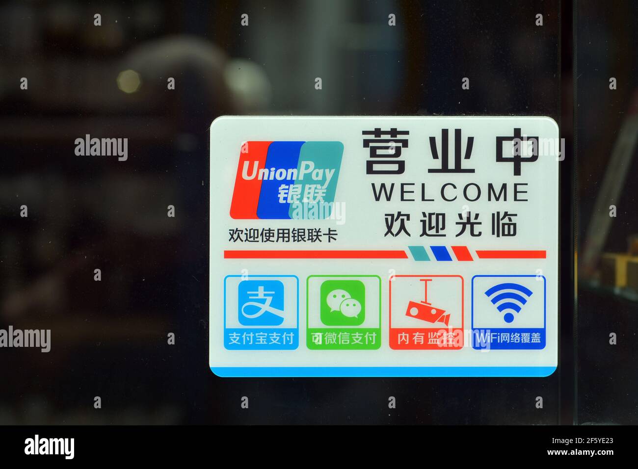 Sign on a door to a Chinese shop. Showing the common payment types of Alipay and Wechat as well as WIFI and security cameras. Stock Photo