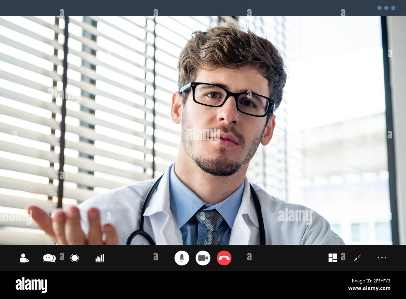 Young male doctor giving online medical consultation to patient via video calling application Stock Photo