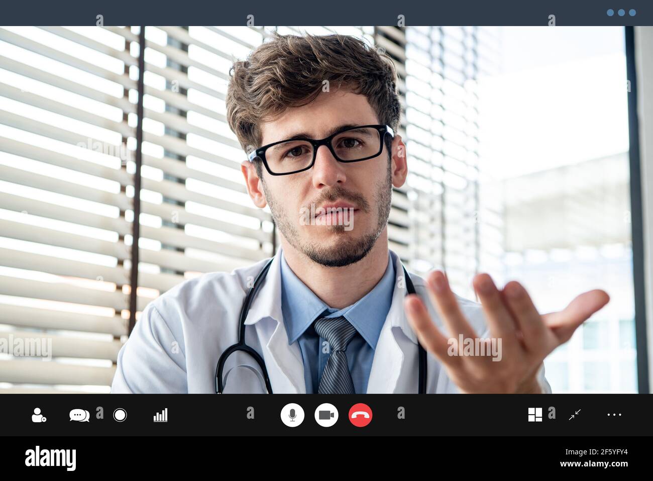 Young male doctor giving online medical consultation to patient via video calling application Stock Photo