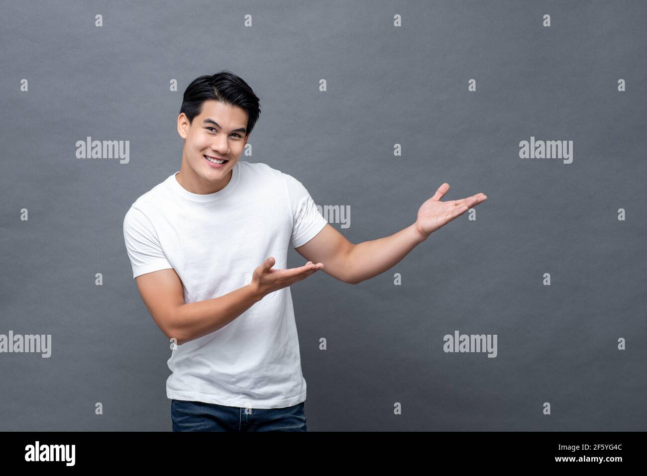 Portrait of young Asian man smiling with open palm gesture isolated on ...