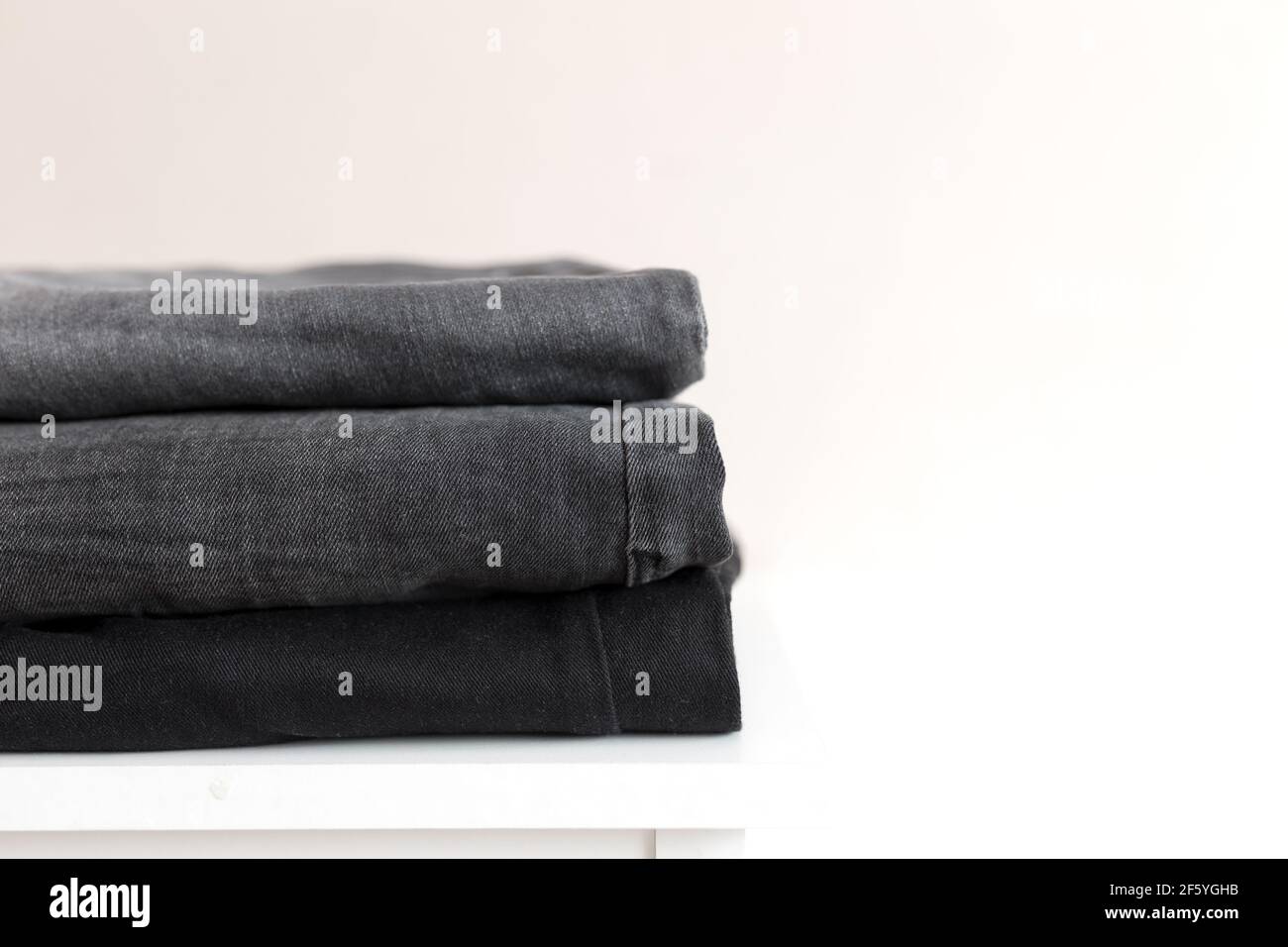A stack of black denim jean pants. Textile industry concept. Clothing stores concept. Sale concept. High quality photo Stock Photo