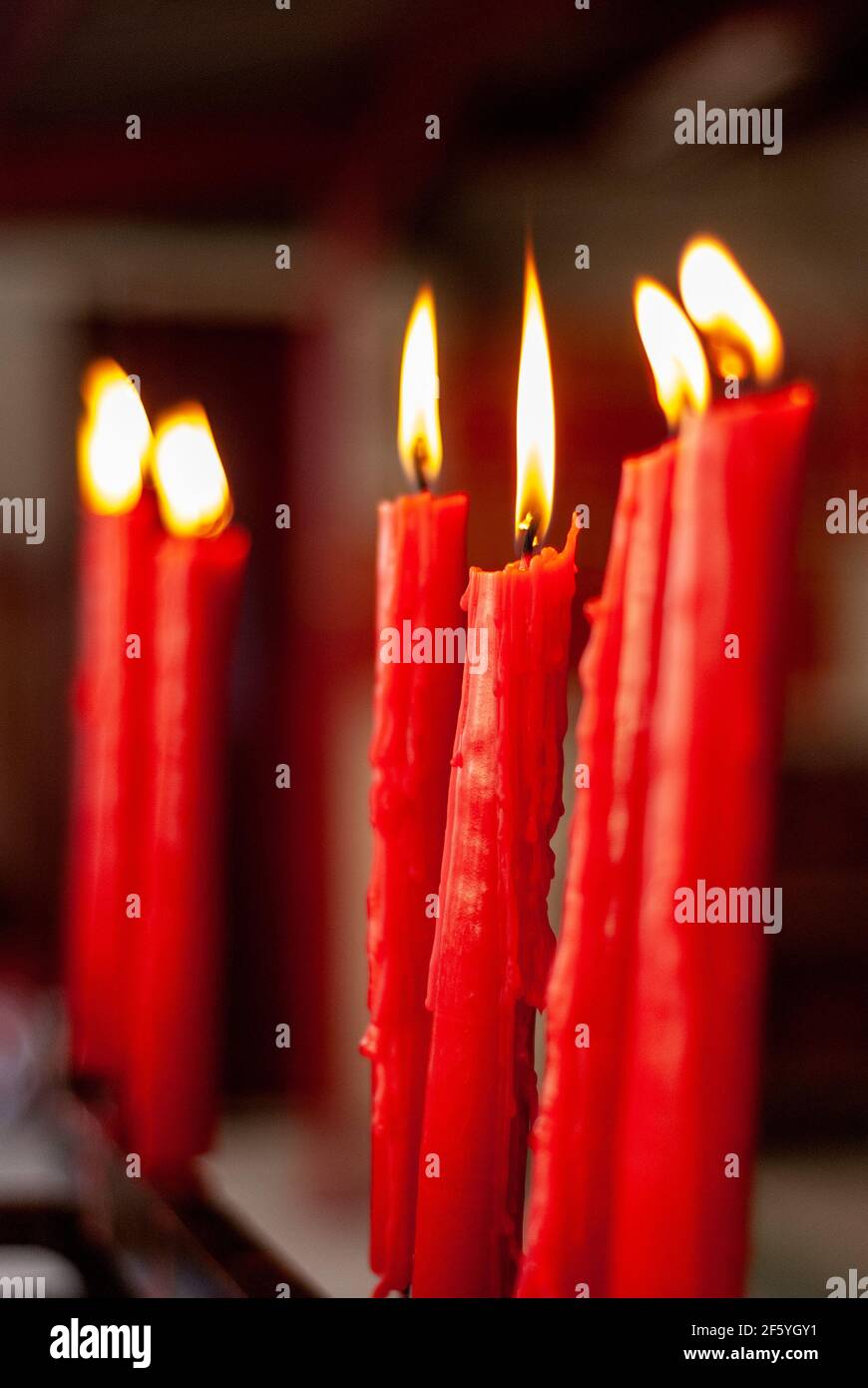 Lit candles inside a Catholic church frequented by faith devotees Stock Photo