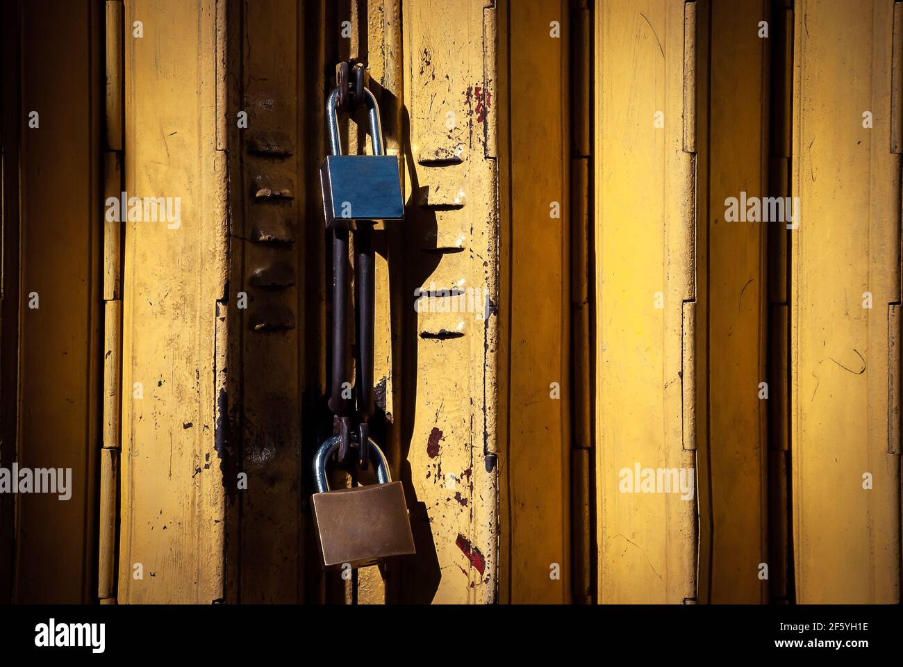 A business establishment closed by yellow gate and secured by two padlocks. Close up shot taken early in the morning. Stock Photo