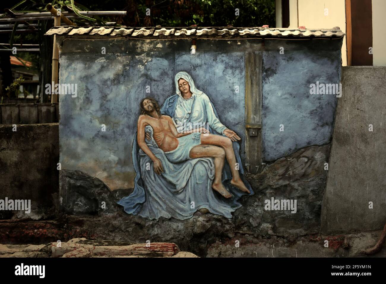 A bas-relief depicting Mother Mary cradling the dead body of Jesus, created by unidentified artist on a wall near the St Ignatius Loyola church, Sikka. Stock Photo
