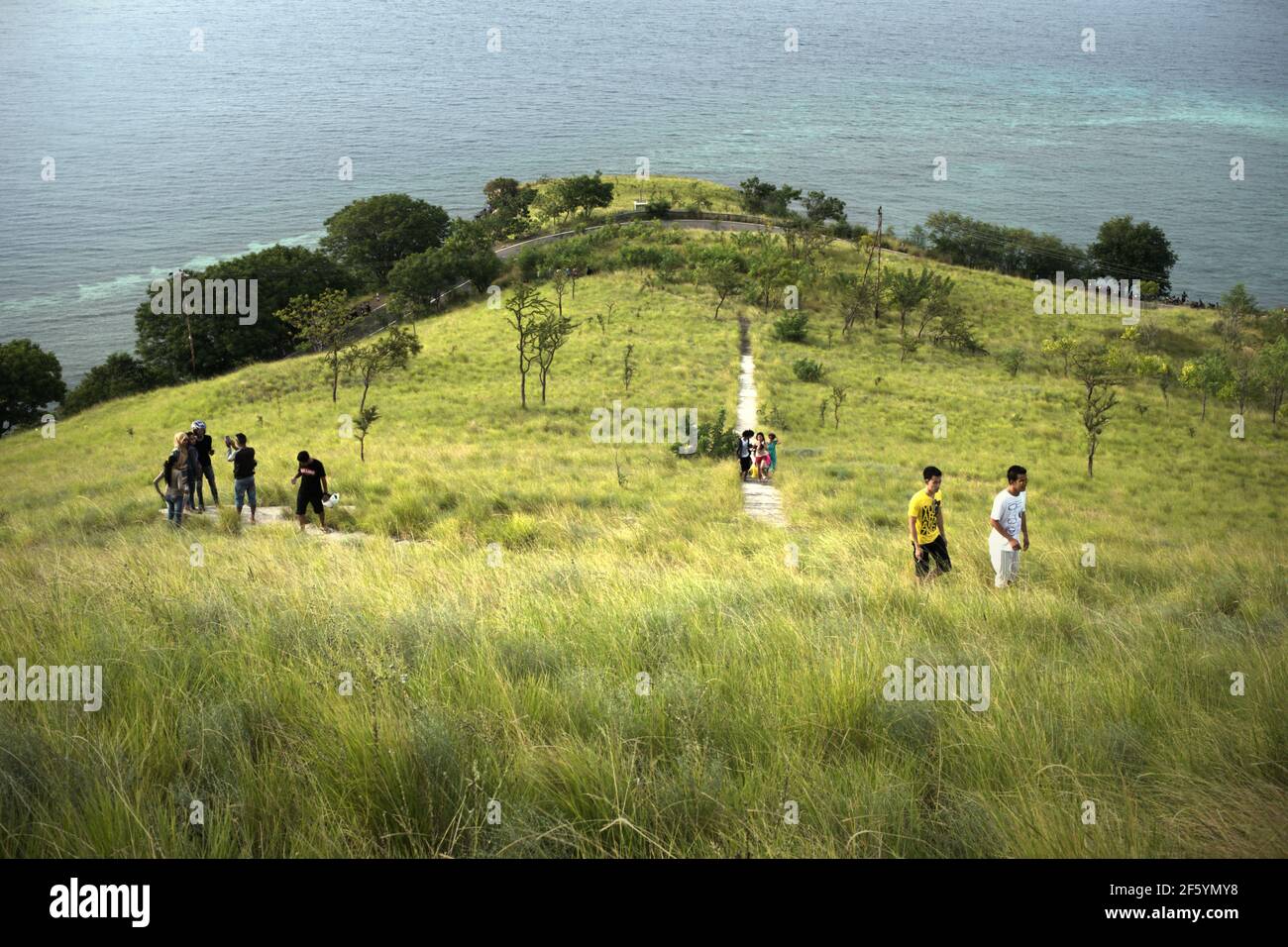 Young people having recreational time by walking on stoned steps through grassland in Kajuwulu near Maumere, Flores Island. Stock Photo
