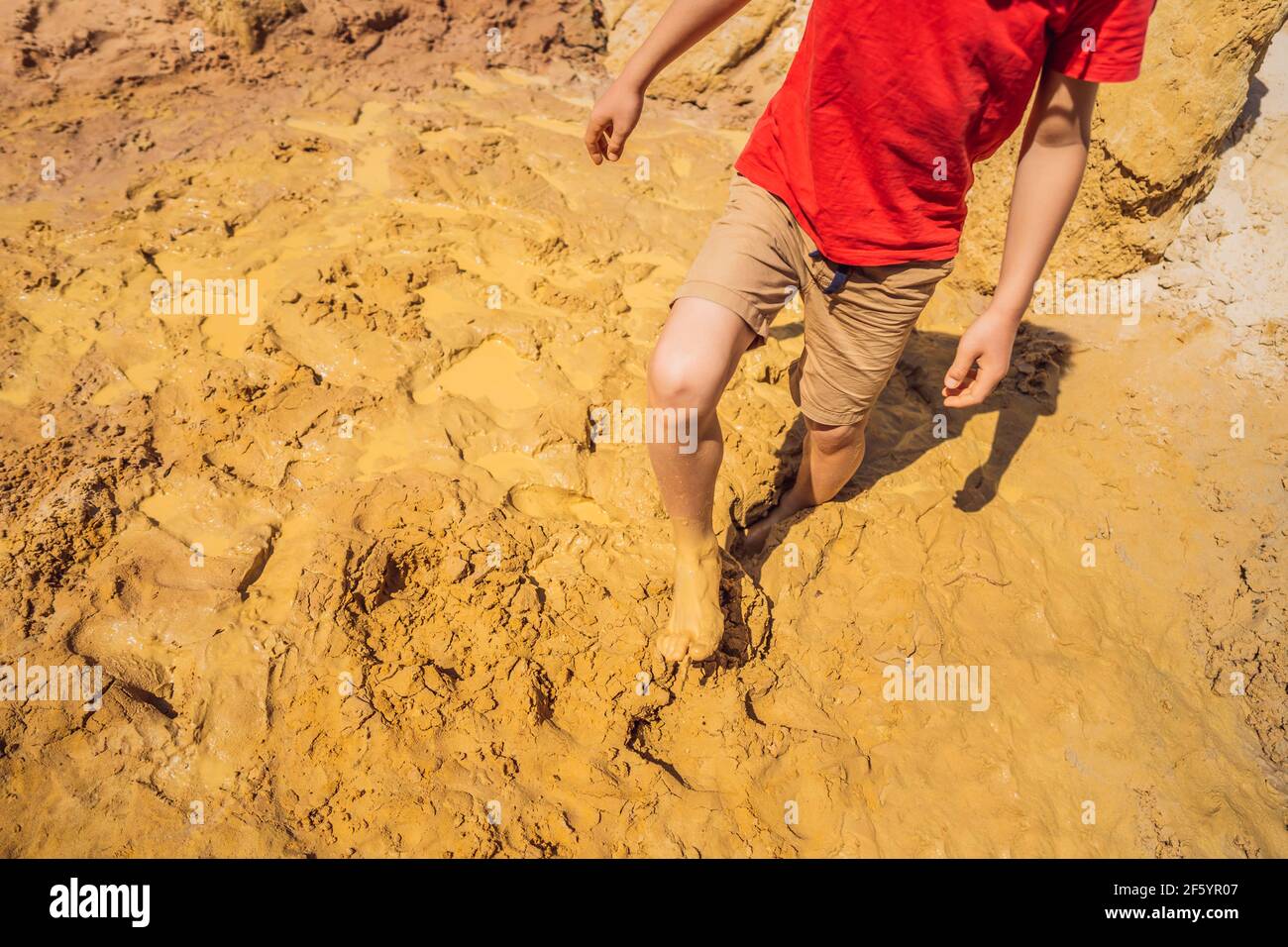 Unlucky person standing in natural quicksand river, clay sediments, sinking, drowning quick sand, stuck in the soil, trapped and stuck concept Stock Photo