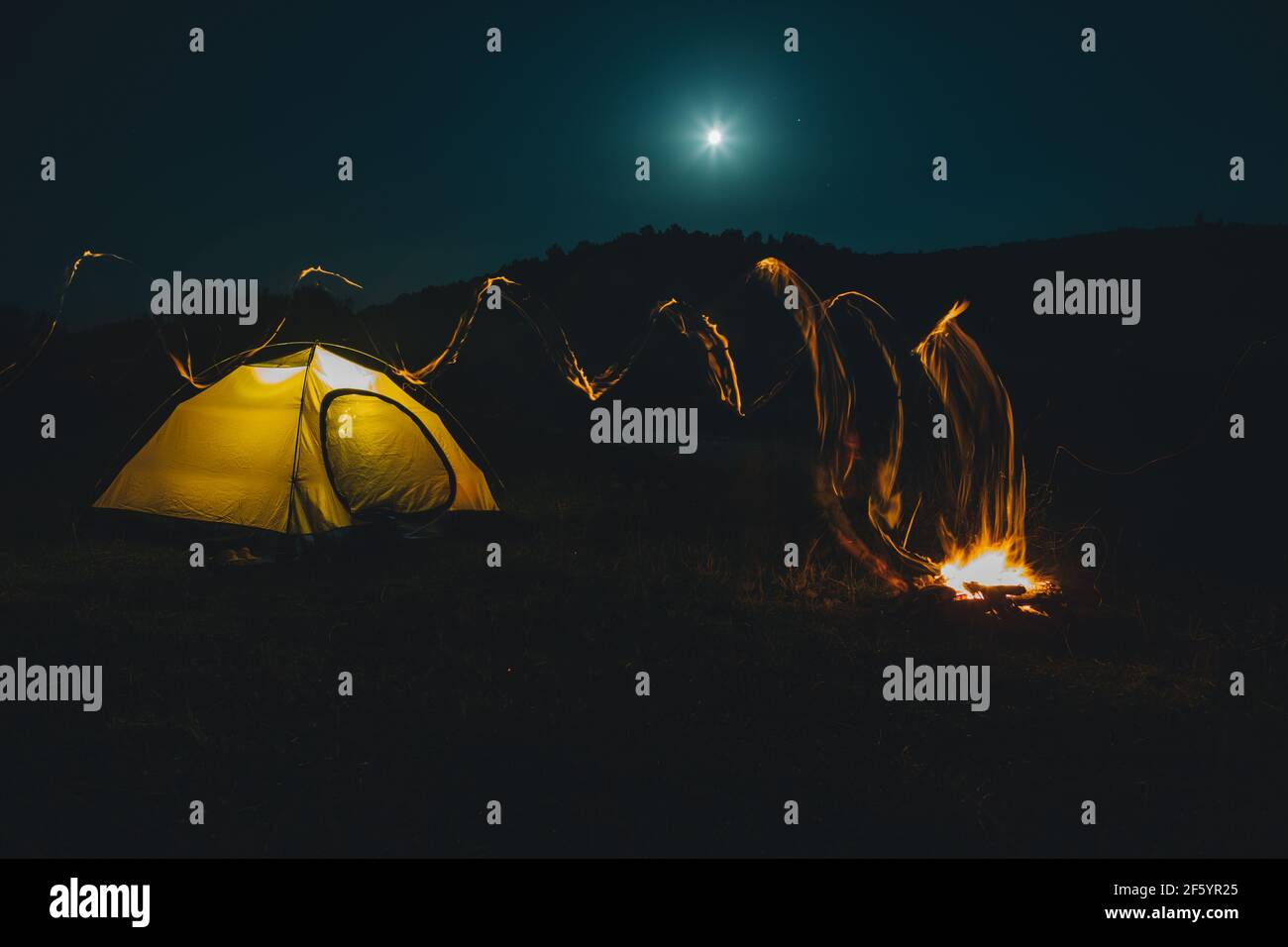 long exposure bonfire with yellow tent on background copy space Stock