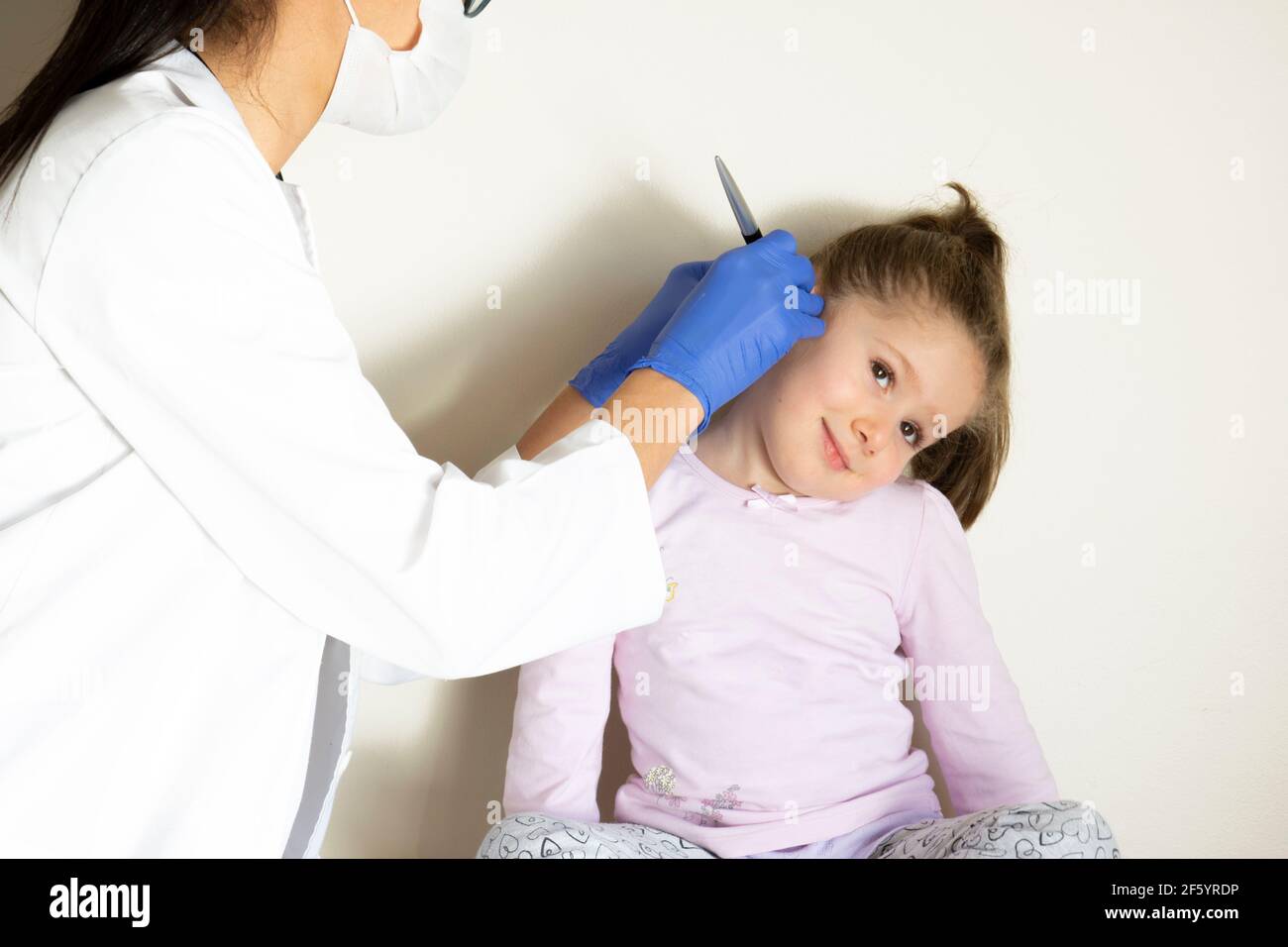 chubby little girl in pediatric examination by her doctor. ENT ( Ear