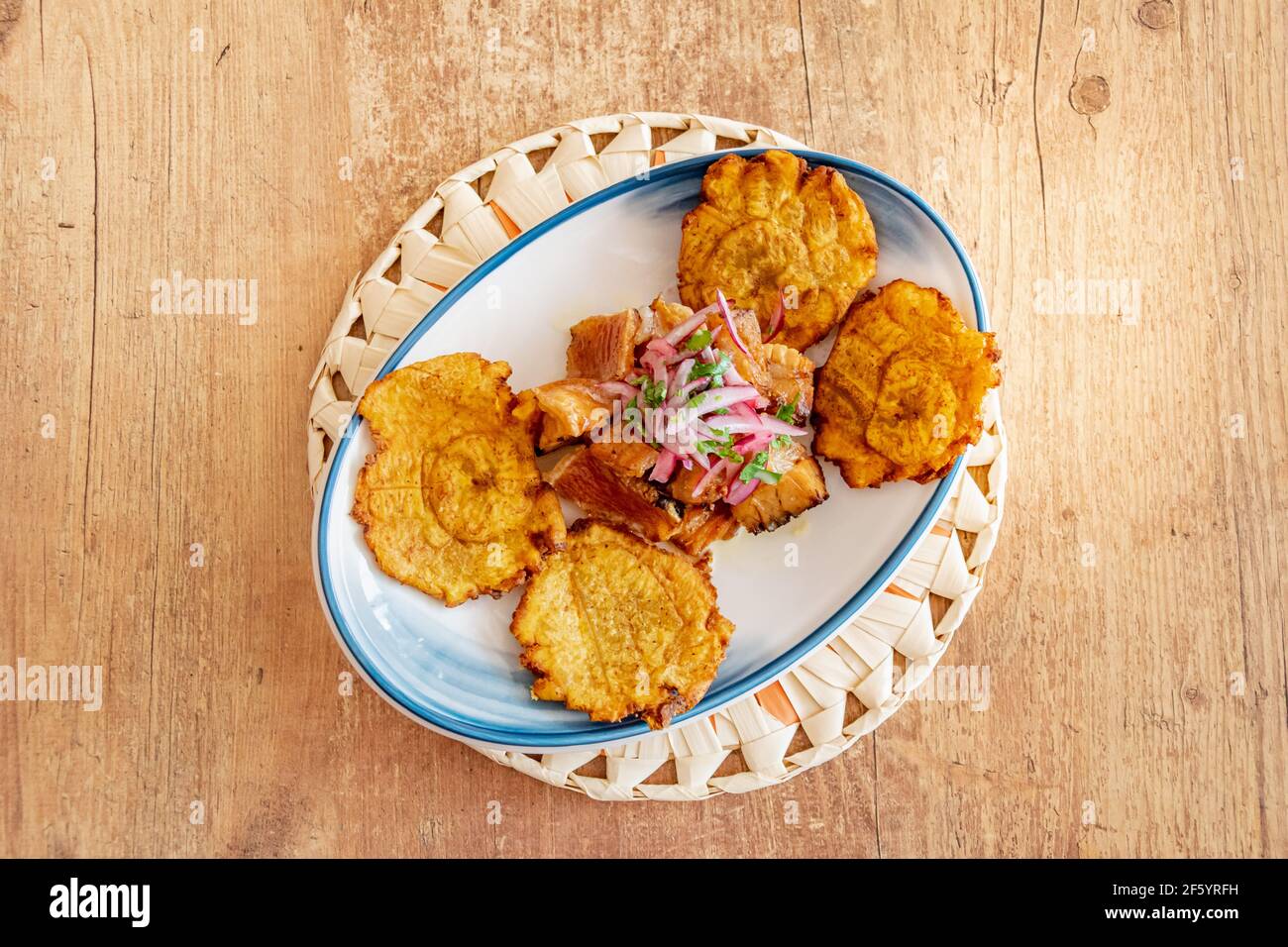 a plate of fried plantain served with shredded beef drizzled with onion