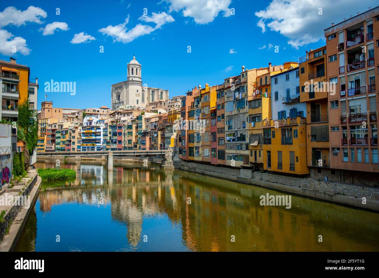 Girona, Spain - July 28, 2019: Beautiful colorful riverside houses in the Jewish quarter of Girona city in Catalunya, Spain, with Girona Cathedral in Stock Photo