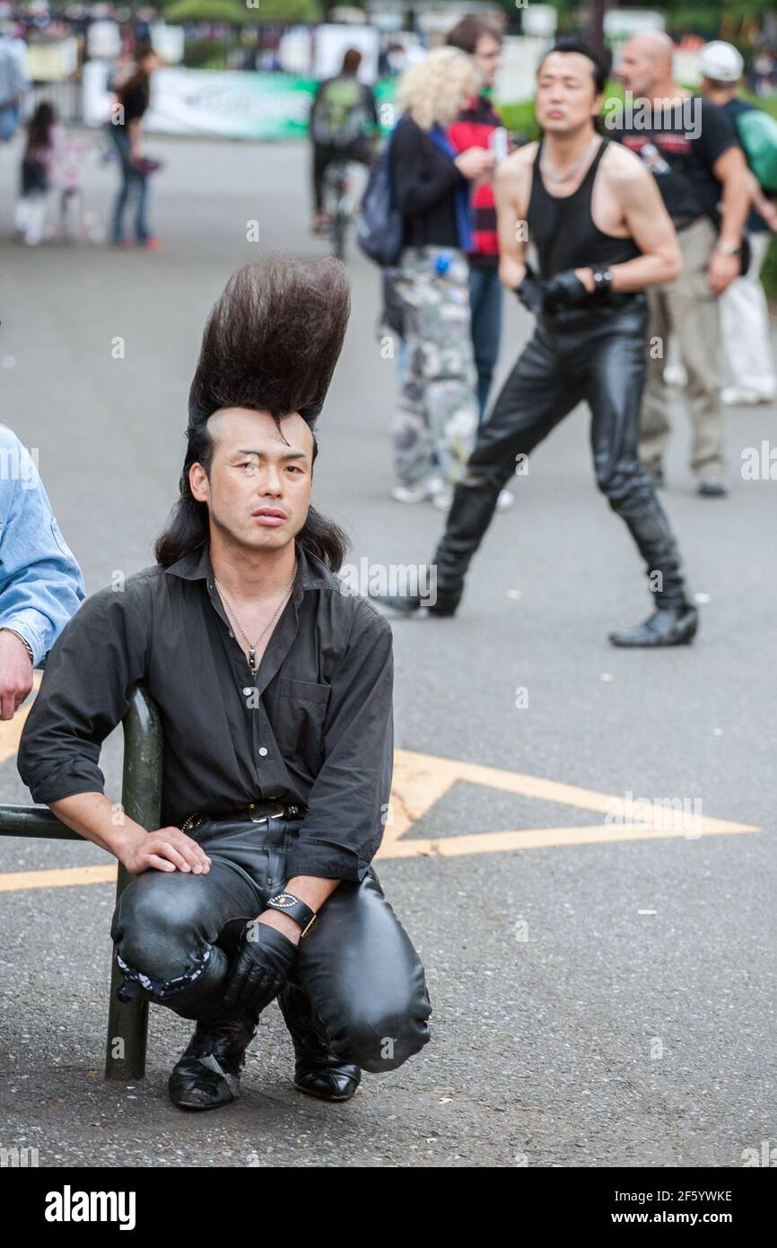 Close up of Rockabilly in leather pants with huge quiff/pompadour, with another dancing rock'n'roll behind, Yoyogi Park, Harajuku, Tokyo, Japan Stock Photo