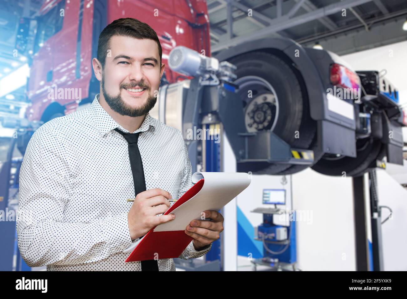 Serviceman with notepad on the background of the truck in the garage Stock Photo
