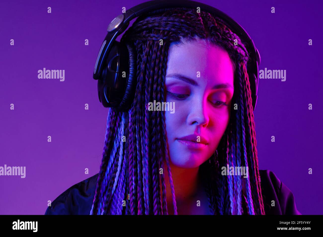 Beautiful woman with long hair in braids listening to music with ...