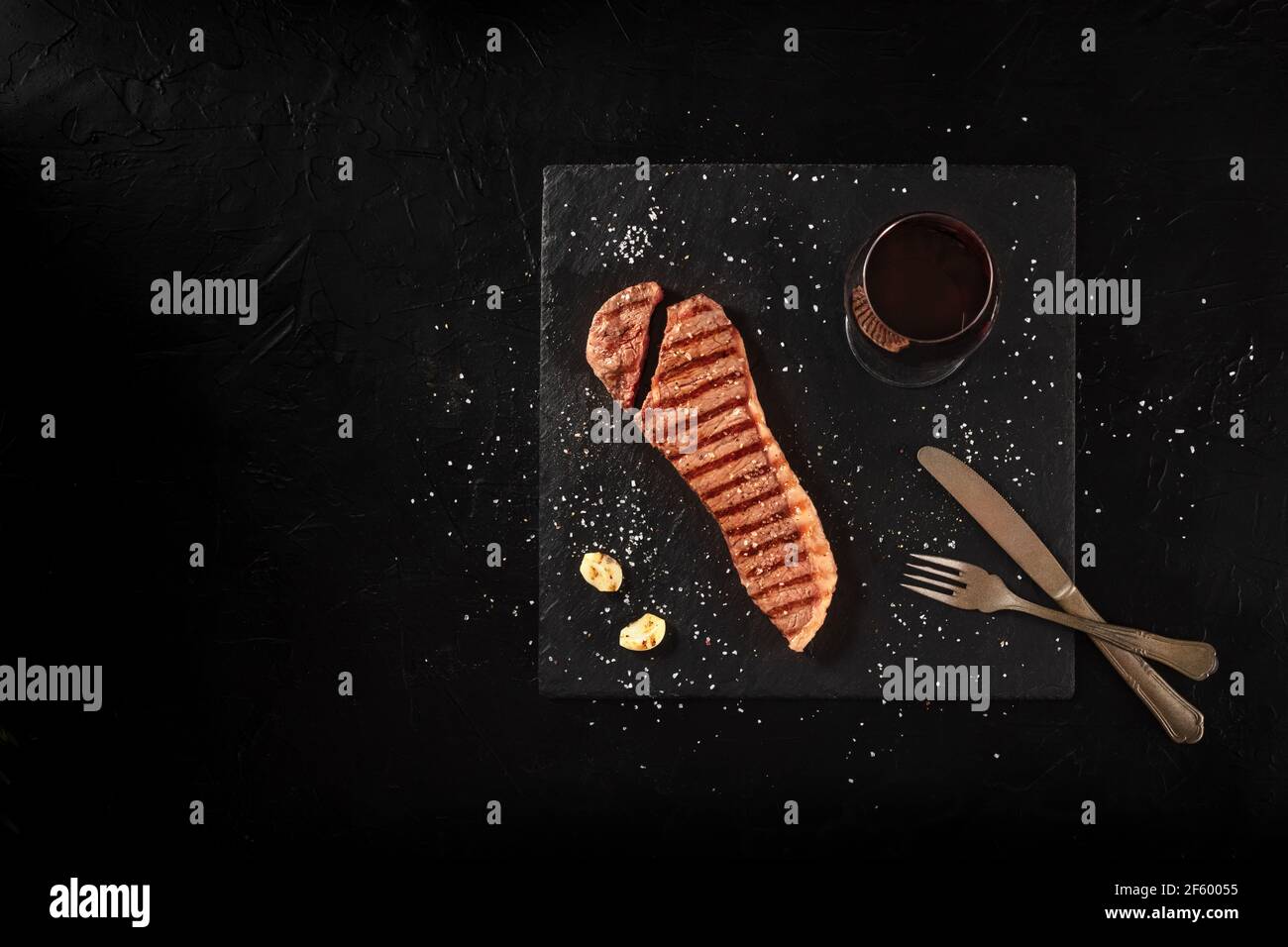Cooked strip steak, cut, shot from above on a black background Stock Photo