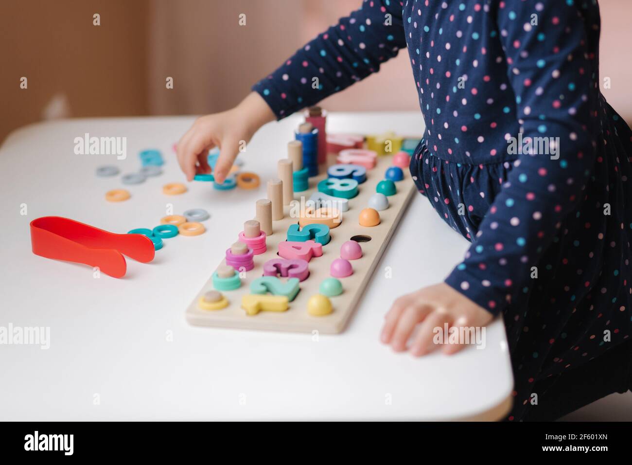 Children Using Color Rods Closeup of kid's hand putting color rings on wooden column. Little girl ...