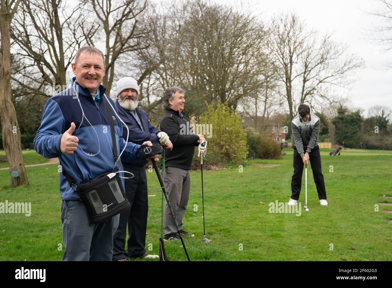 London, UK. March 29, 2021, London, UK: Covid survivor, David Sheridan, prepares to tee off at Brent Valley Golf Course on the day golf returns as part of the government’s roadmap out of lockdown. Mr Sheridan, who still carries an oxygen machine and monitors his oxygen levels, was in intensive care for one month with covid-19 and was discharged on March 5. Past captain at Brent Valley Golf Club, he planned to play 18 holes but was accompanied by his brother in case he couldn’t complete the round. Photo: Roger Garfield/Alamy Live News Stock Photo